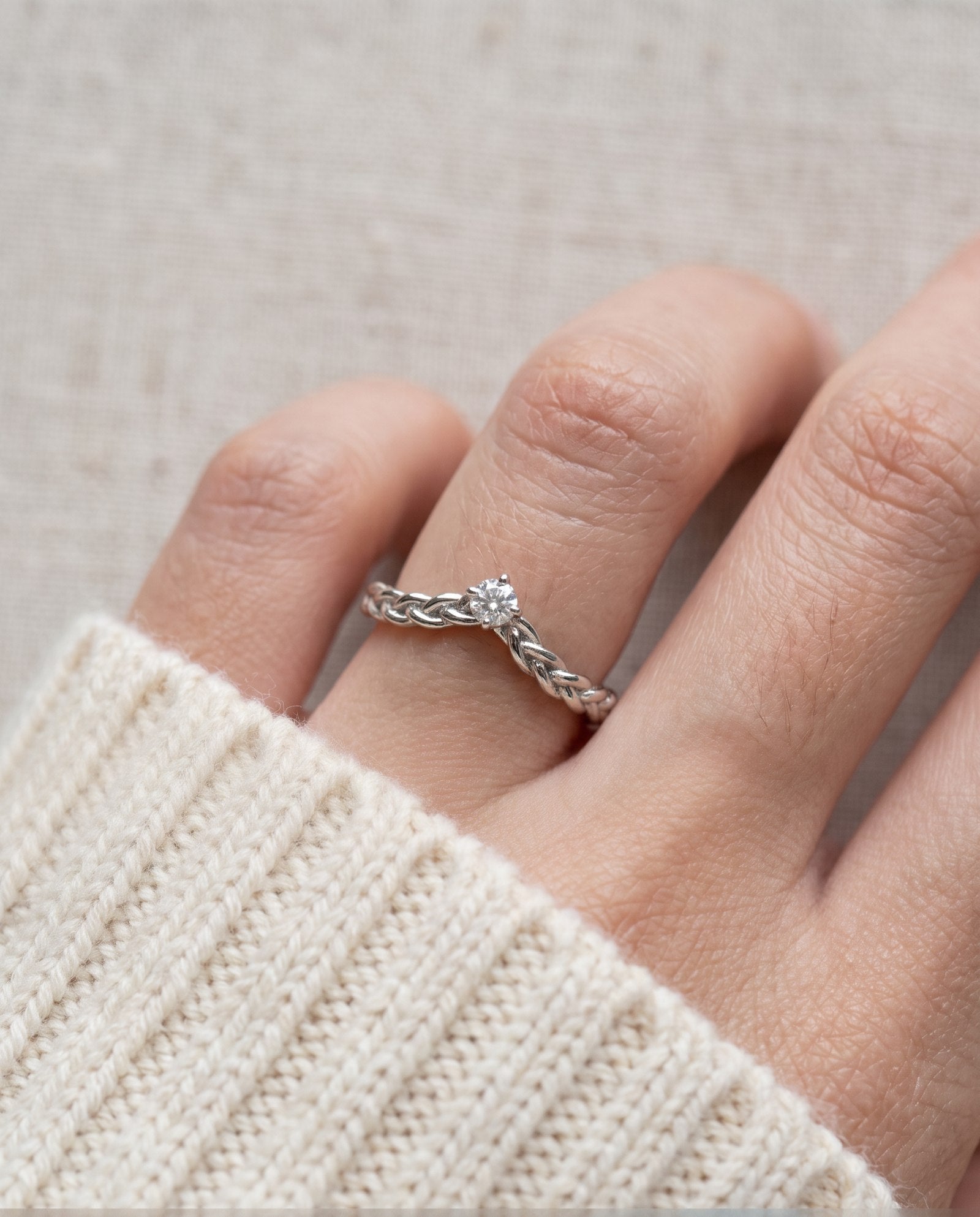 Model wearing a sterling silver Braided Wishbone White Moissanite Ring worn solo on middle finger.