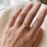 Model wearing a yellow gold vermeil Braided Wishbone White Moissanite Ring styled on middle finger between simple gold bands.