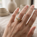 Model wearing a yellow gold Braided Wishbone White Moissanite Ring stacked below a round solitaire ring with simple gold bands.