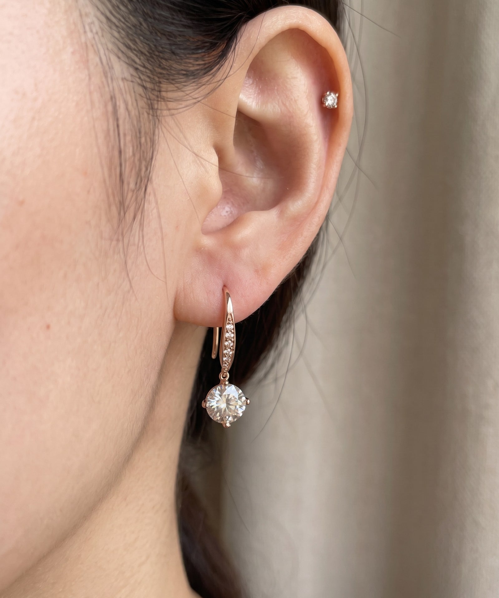 Side-profile view of a model wearing a rose gold off-white moissanite ear hook with pavé wire accents.