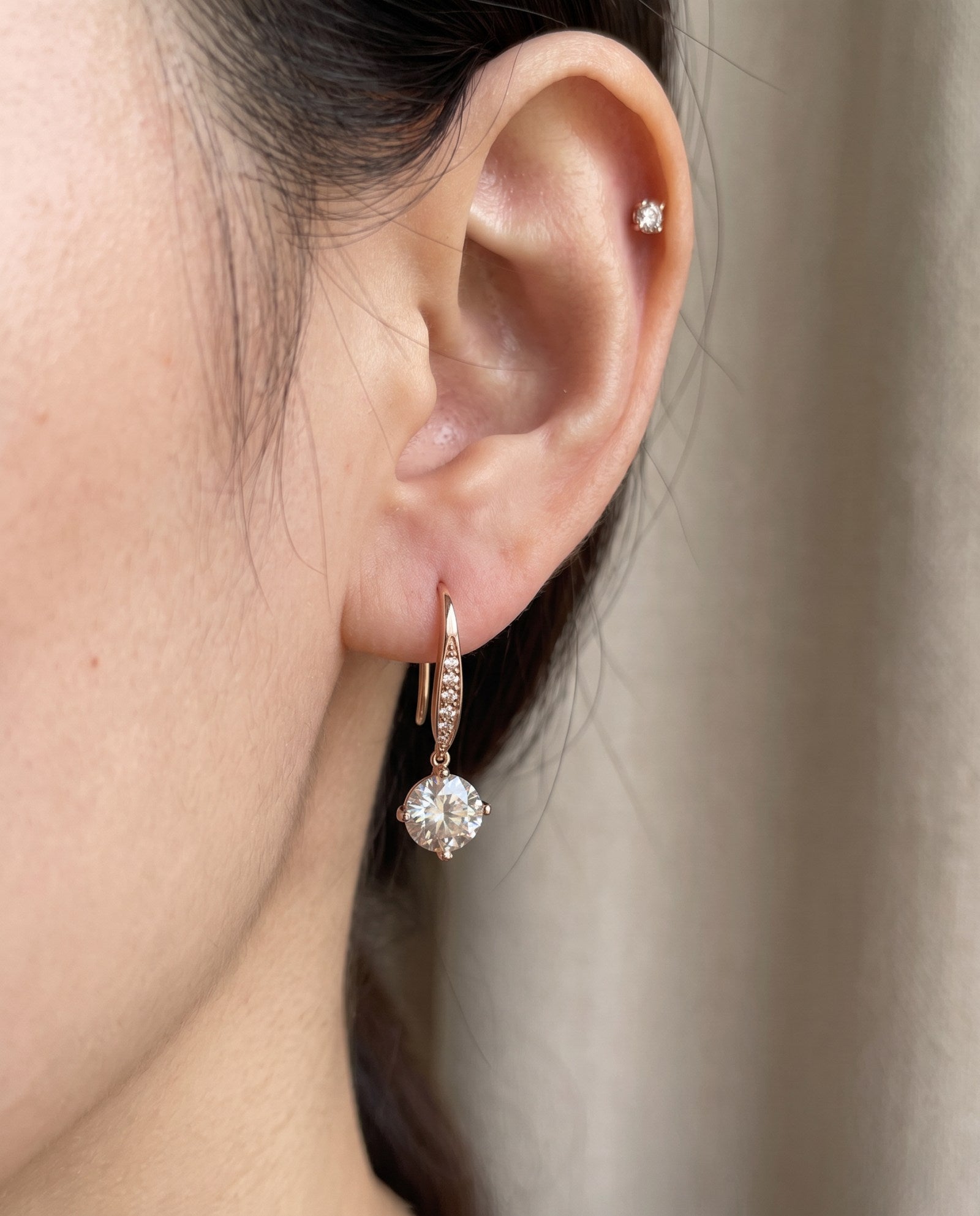 Side-profile view of a model wearing a rose gold off-white moissanite ear hook with pavé wire accents.