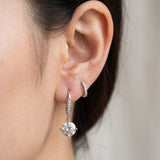 Close-up view of a silver Candlelight Moissanite Solitaire Hook stacked with a delicate pavé huggie hoop.