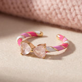 Candy Cane Ribbon Ring | Rose Quartz in yellow gold, laid flat on a tabletop