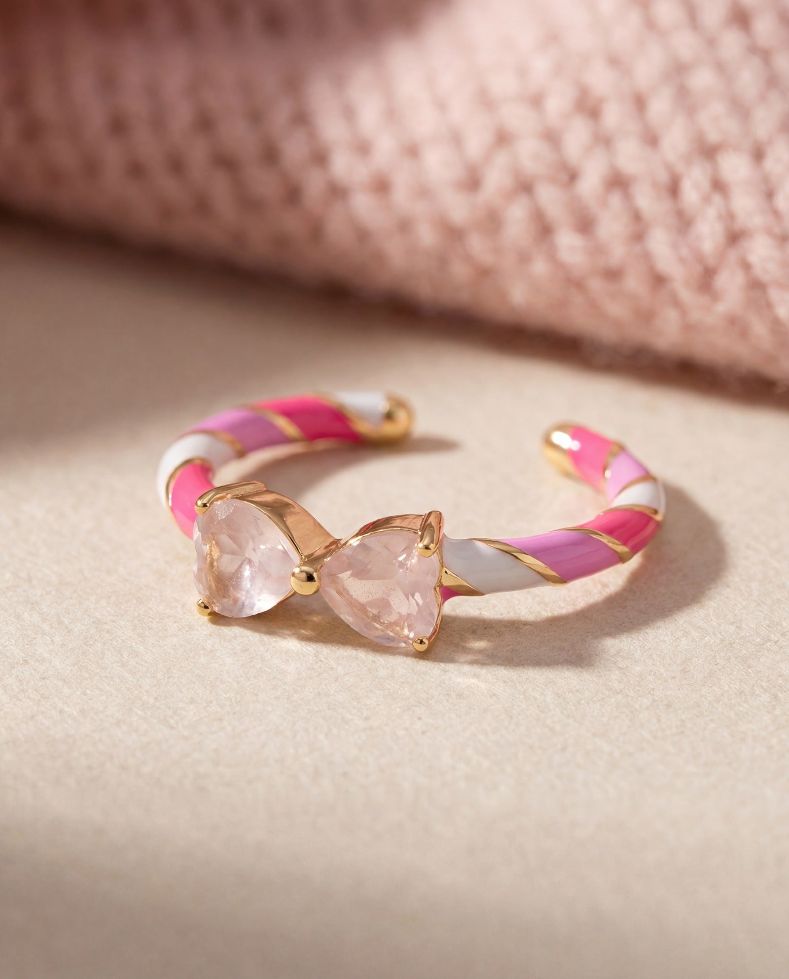 Candy Cane Ribbon Ring | Rose Quartz in yellow gold, laid flat on a tabletop
