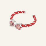 Candy Cane Ribbon Ring | Red Moissanite in silver, resting on a warm linen background