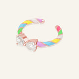 Candy Cane Ribbon Ring | White Moissanite in rose gold, resting on a warm linen background
