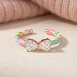 Candy Cane Ribbon Ring | White Moissanite in rose gold, laid flat on a tabletop