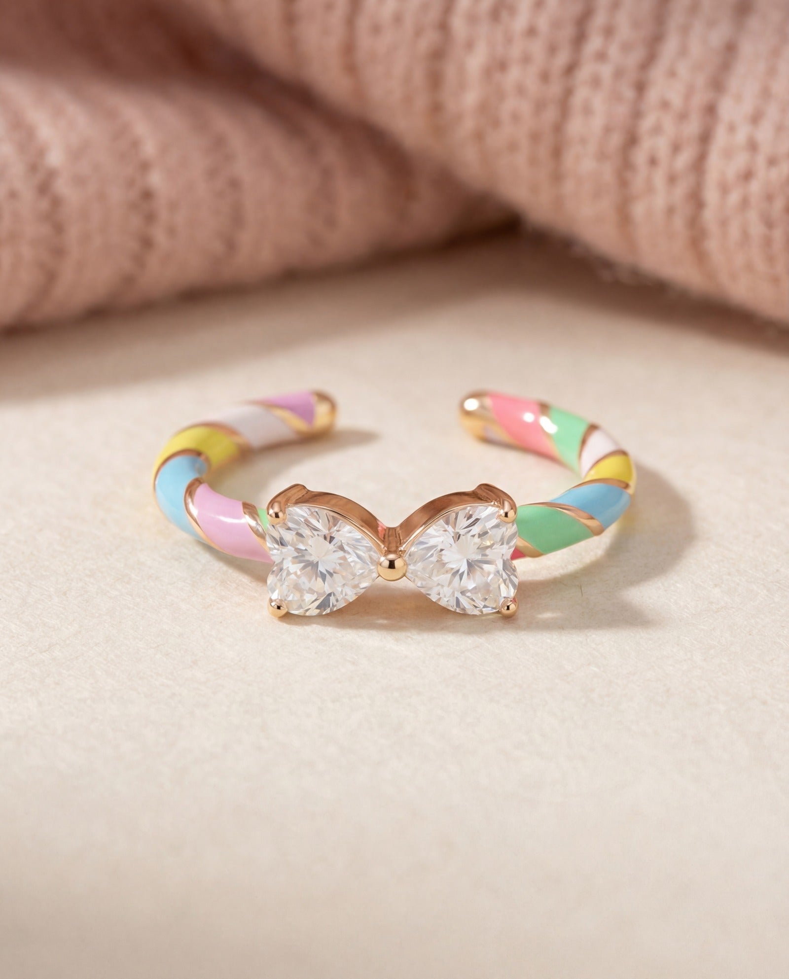 Candy Cane Ribbon Ring | White Moissanite in rose gold, laid flat on a tabletop