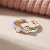 Candy Cane Ribbon Ring | White Moissanite in rose gold, laid flat on a tabletop