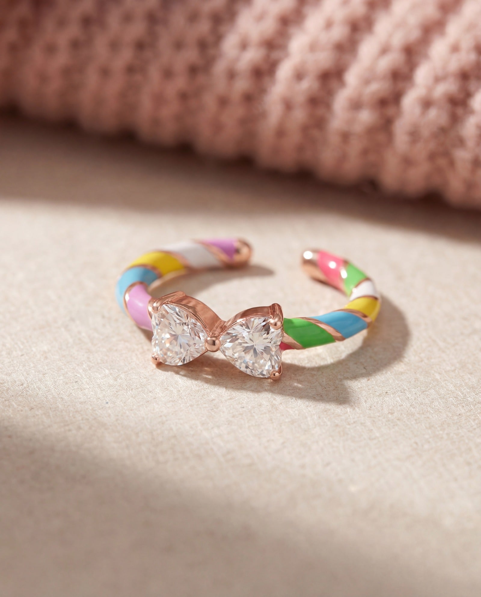 Candy Cane Ribbon Ring | White Moissanite in rose gold, laid flat on a tabletop