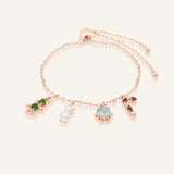 Close-up of the Christmas Charm Bracelet in rose gold, resting on a warm linen background