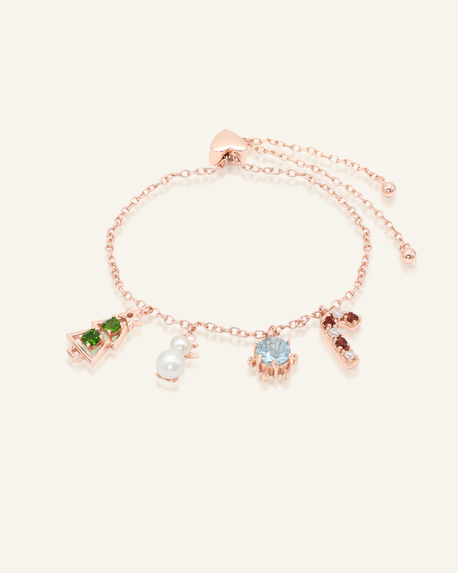 Close-up of the Christmas Charm Bracelet in rose gold, resting on a warm linen background