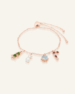 Close-up of the Christmas Charm Bracelet in rose gold, resting on a warm linen background