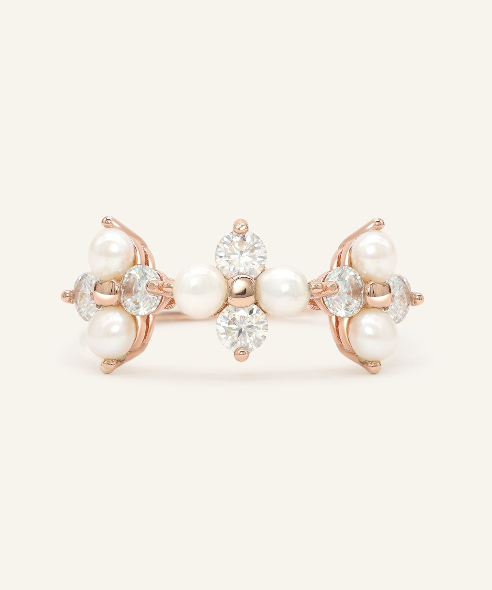 Trinity Clover Ring in rose gold, resting on a warm linen background