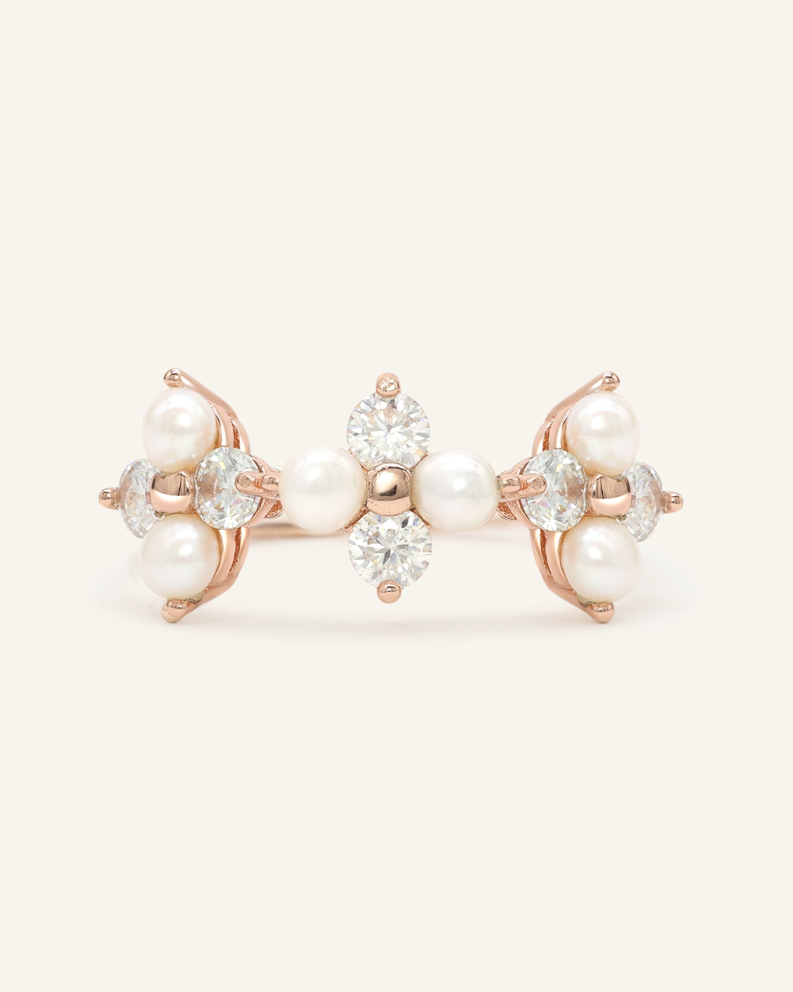 Trinity Clover Ring in rose gold, resting on a warm linen background