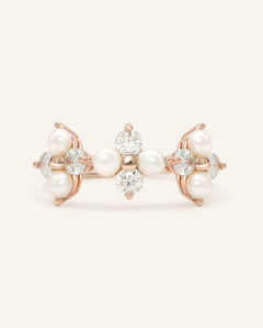 Trinity Clover Ring in rose gold, resting on a warm linen background