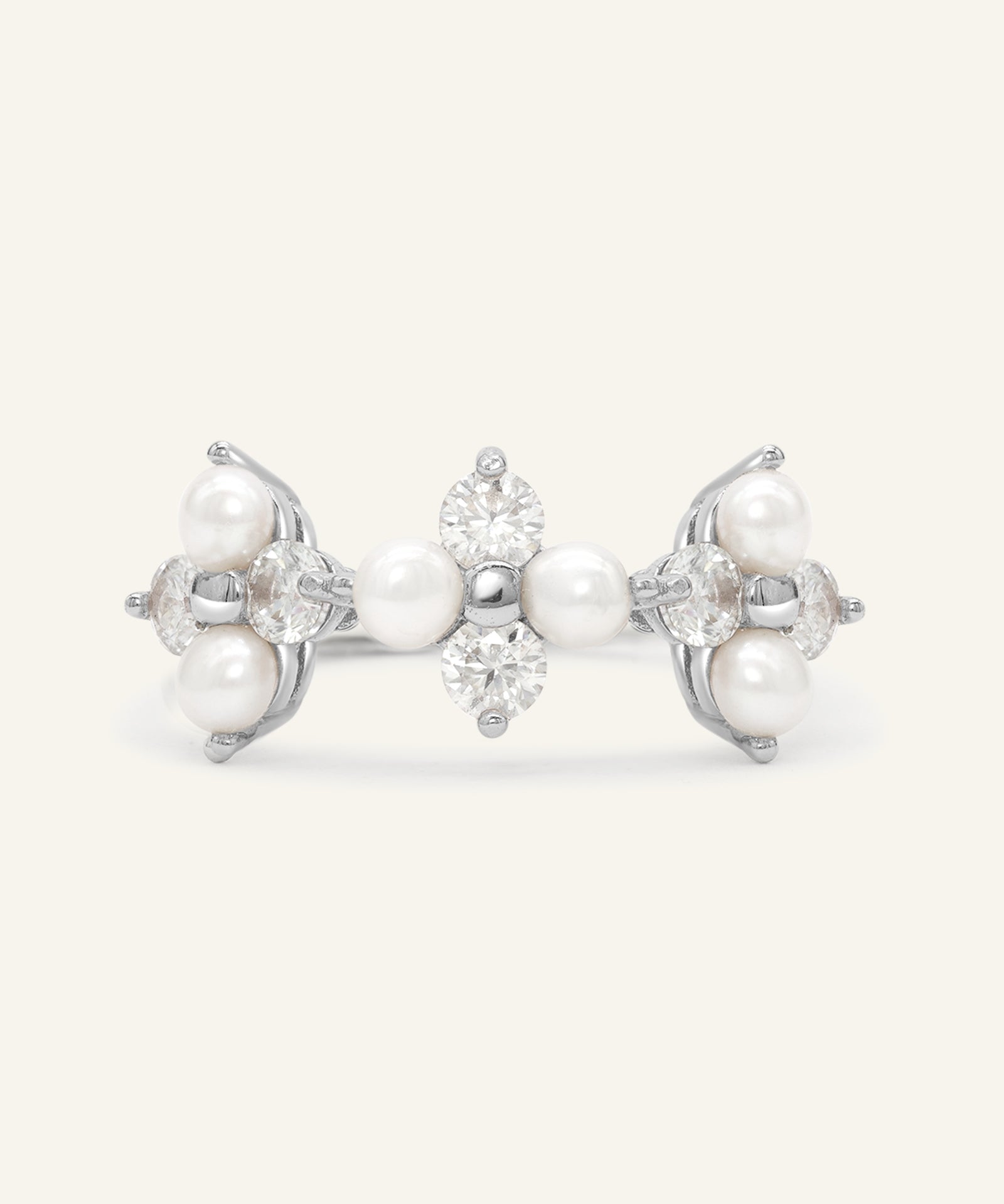 Trinity Clover Ring in silver, resting on a warm linen background