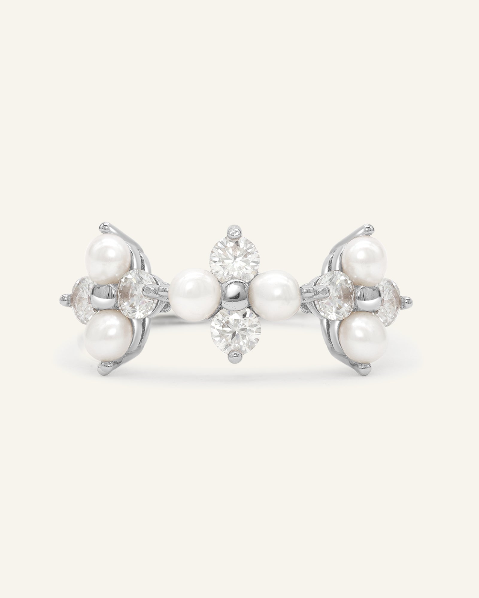 Trinity Clover Ring in silver, resting on a warm linen background