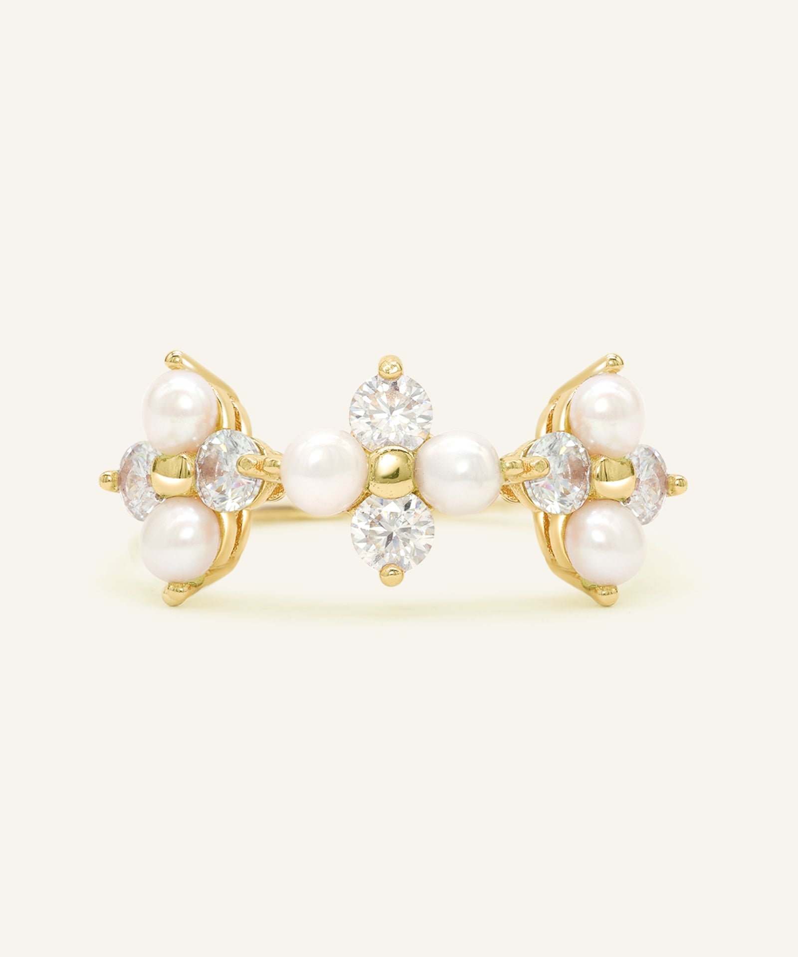 Close-up of the Trinity Clover Ring in yellow gold, resting on a warm linen background