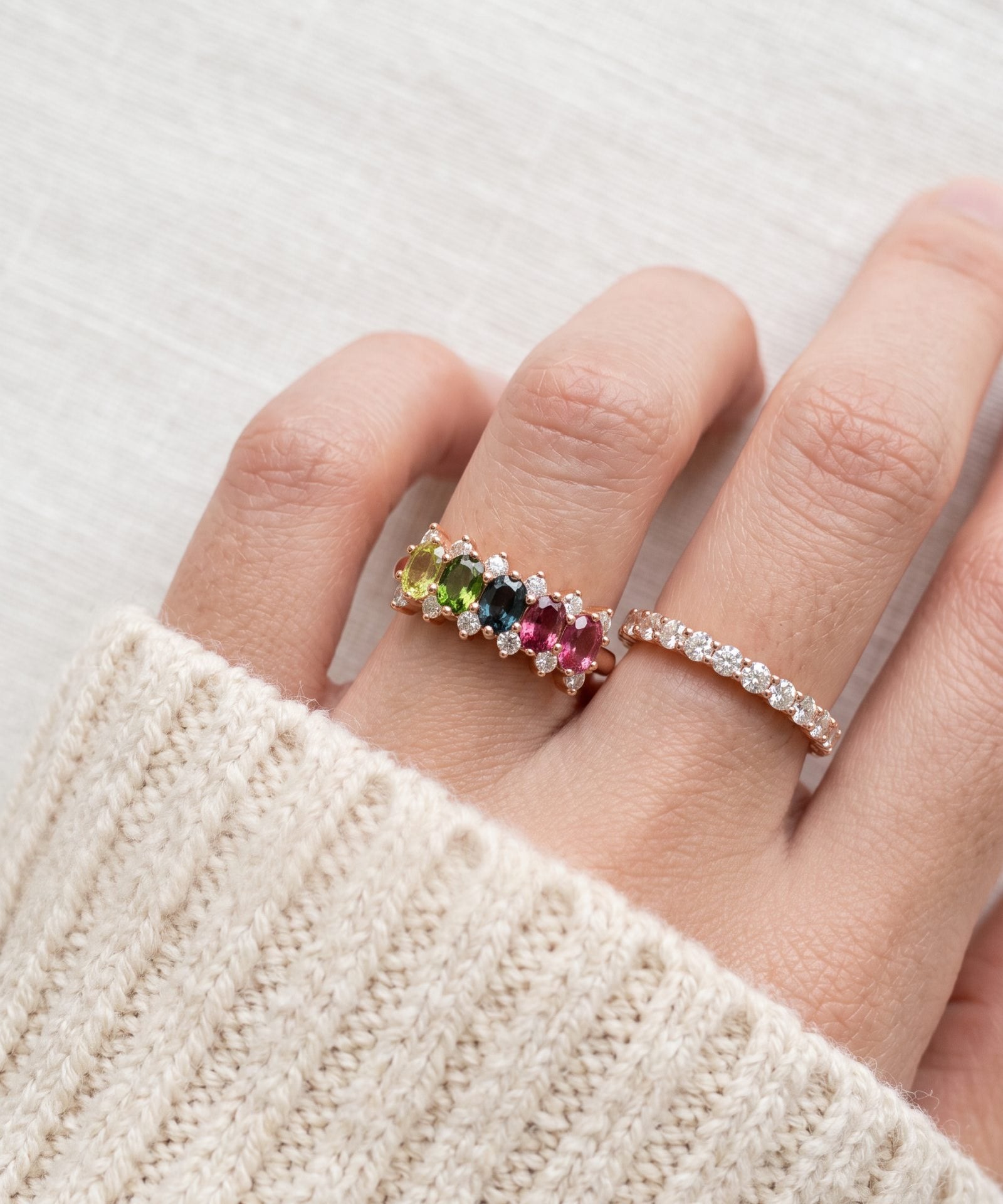 Model wearing a rose gold Color Burst Oval Ring with five natural gemstones stacked next to a delicate pavé band.