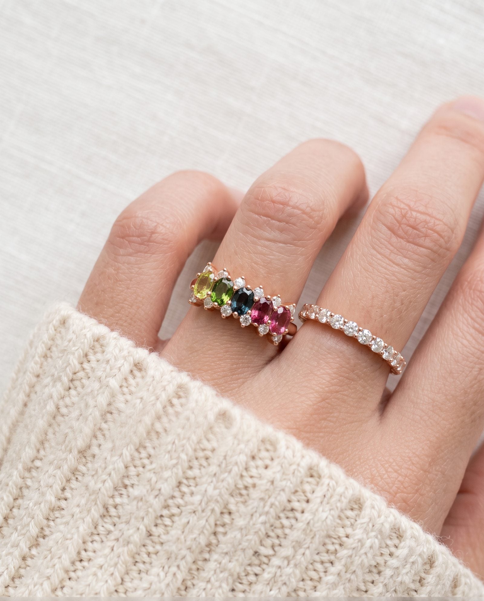 Model wearing a rose gold Color Burst Oval Ring with five natural gemstones stacked next to a delicate pavé band.