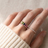 Close-up lifestyle photograph of a model wearing a rose gold multi-gemstone five-stone oval ring.