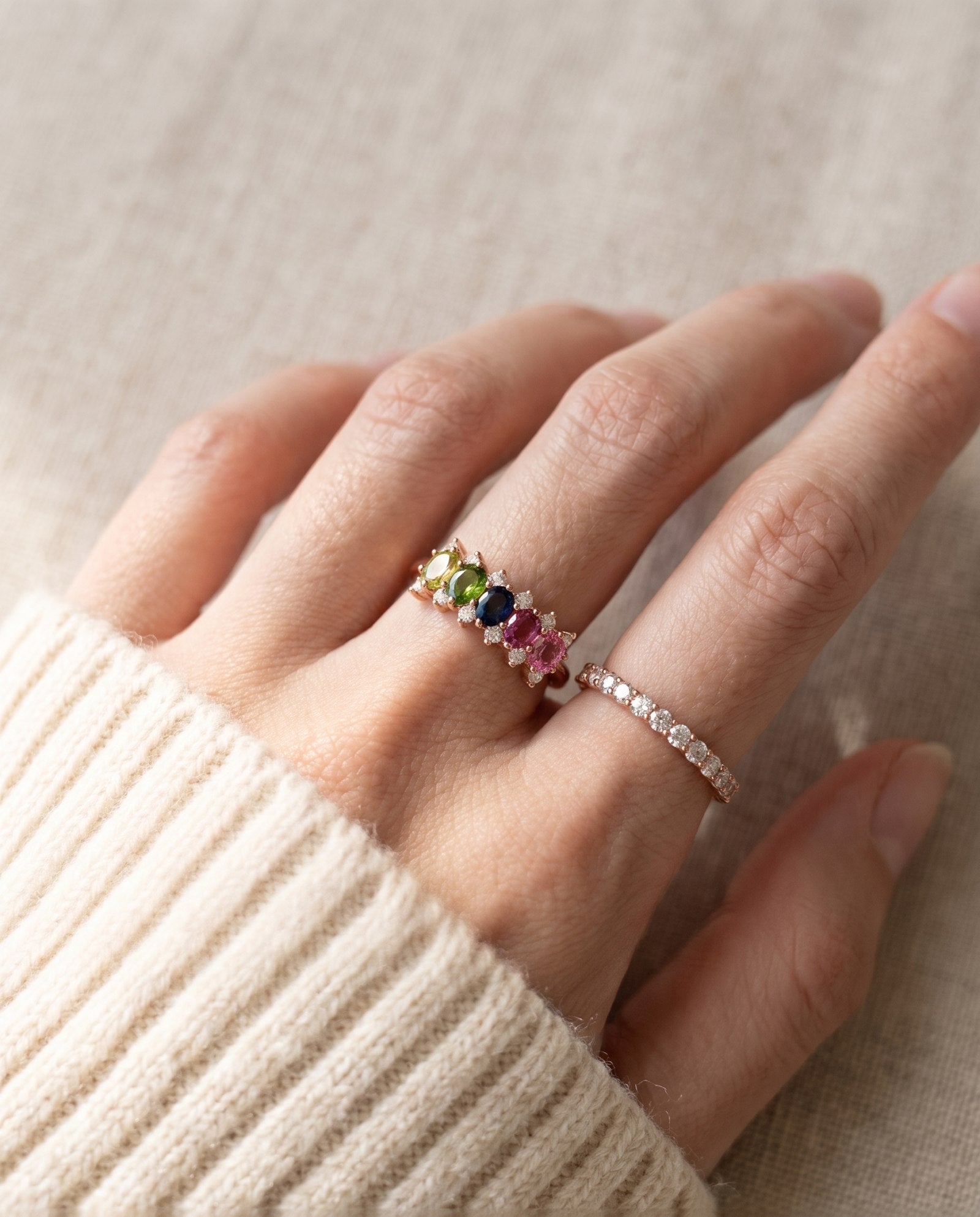 Close-up lifestyle photograph of a model wearing a rose gold multi-gemstone five-stone oval ring.