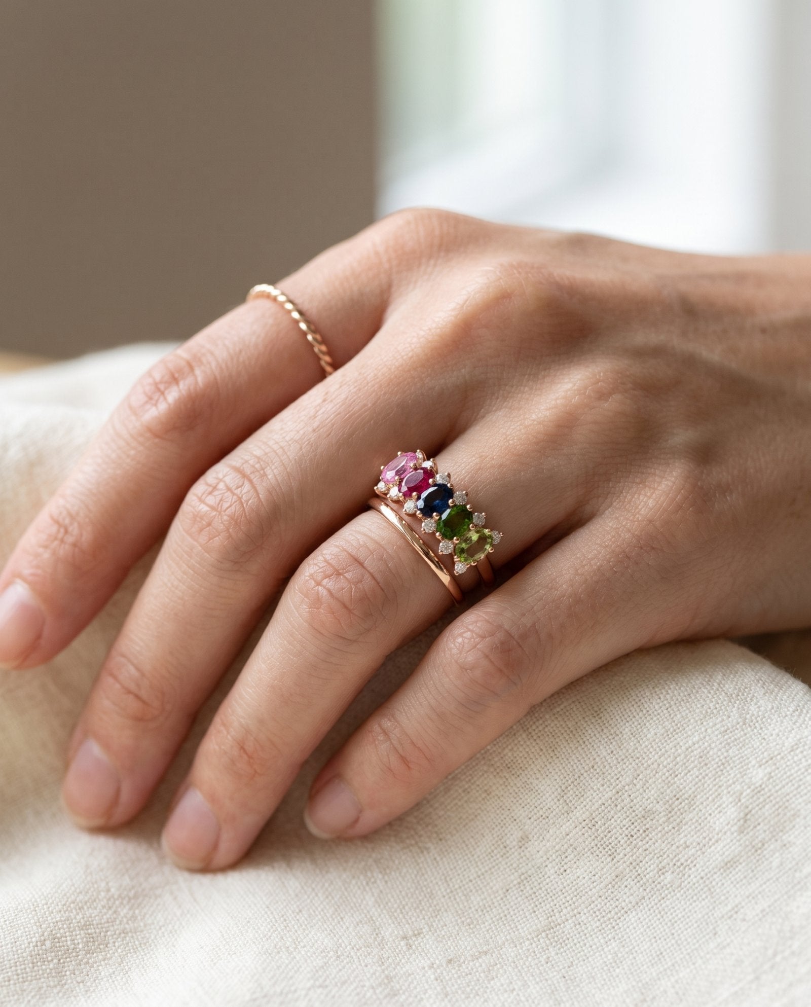 Hand showing a rose gold Color Burst Oval Ring stacked with a simple plain band and a twisted ring.