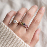 Model wearing a rose gold multi-colored oval stone ring stacked beside a solitaire moissanite ring.