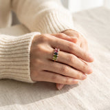 High-angle lifestyle view of model's hands folded, featuring a rose gold oval gemstone statement ring.