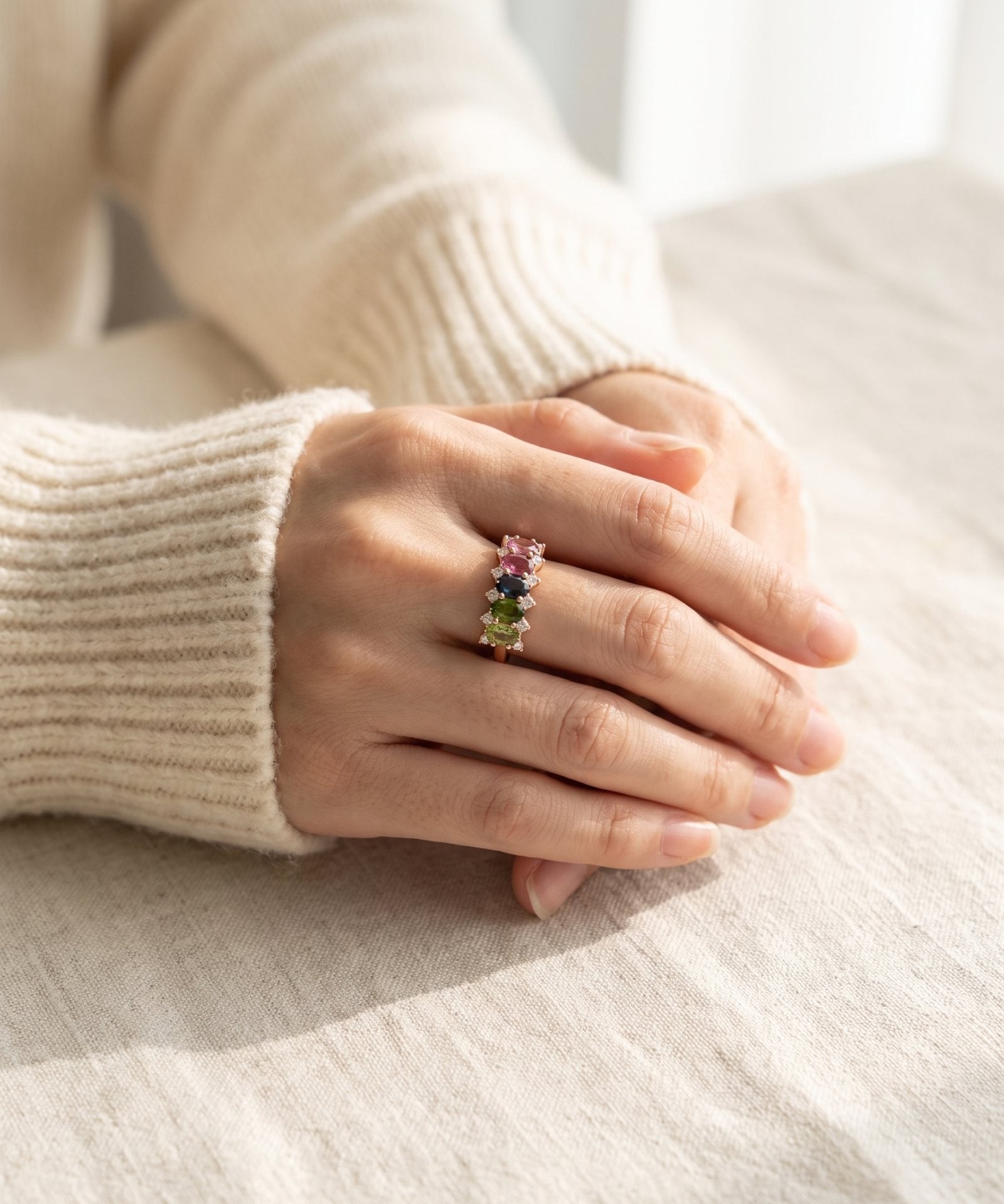 High-angle lifestyle view of model's hands folded, featuring a rose gold oval gemstone statement ring.