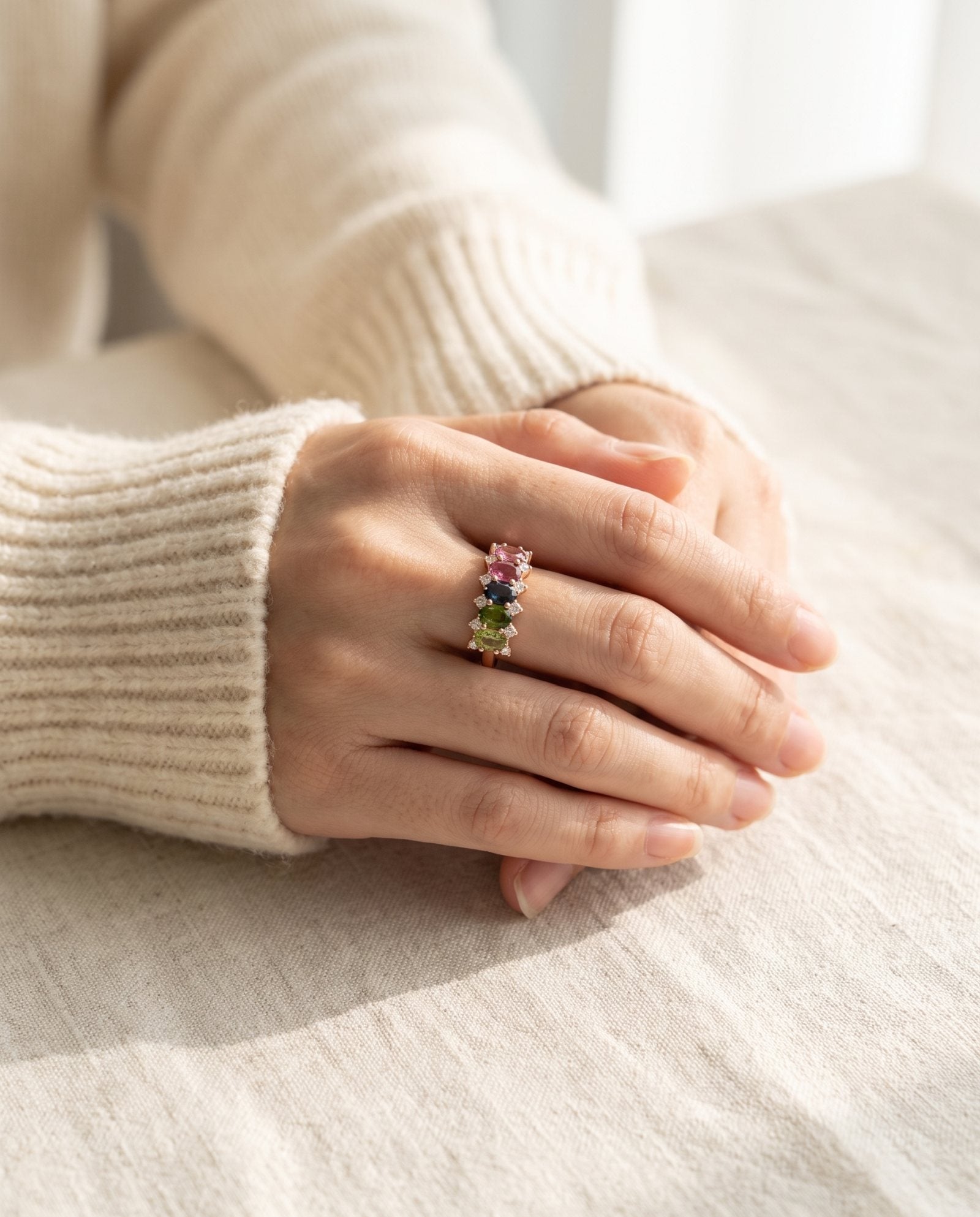 High-angle lifestyle view of model's hands folded, featuring a rose gold oval gemstone statement ring.