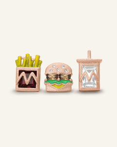 Close-up of the Combo Meal Studs in rose gold, resting on a warm linen background