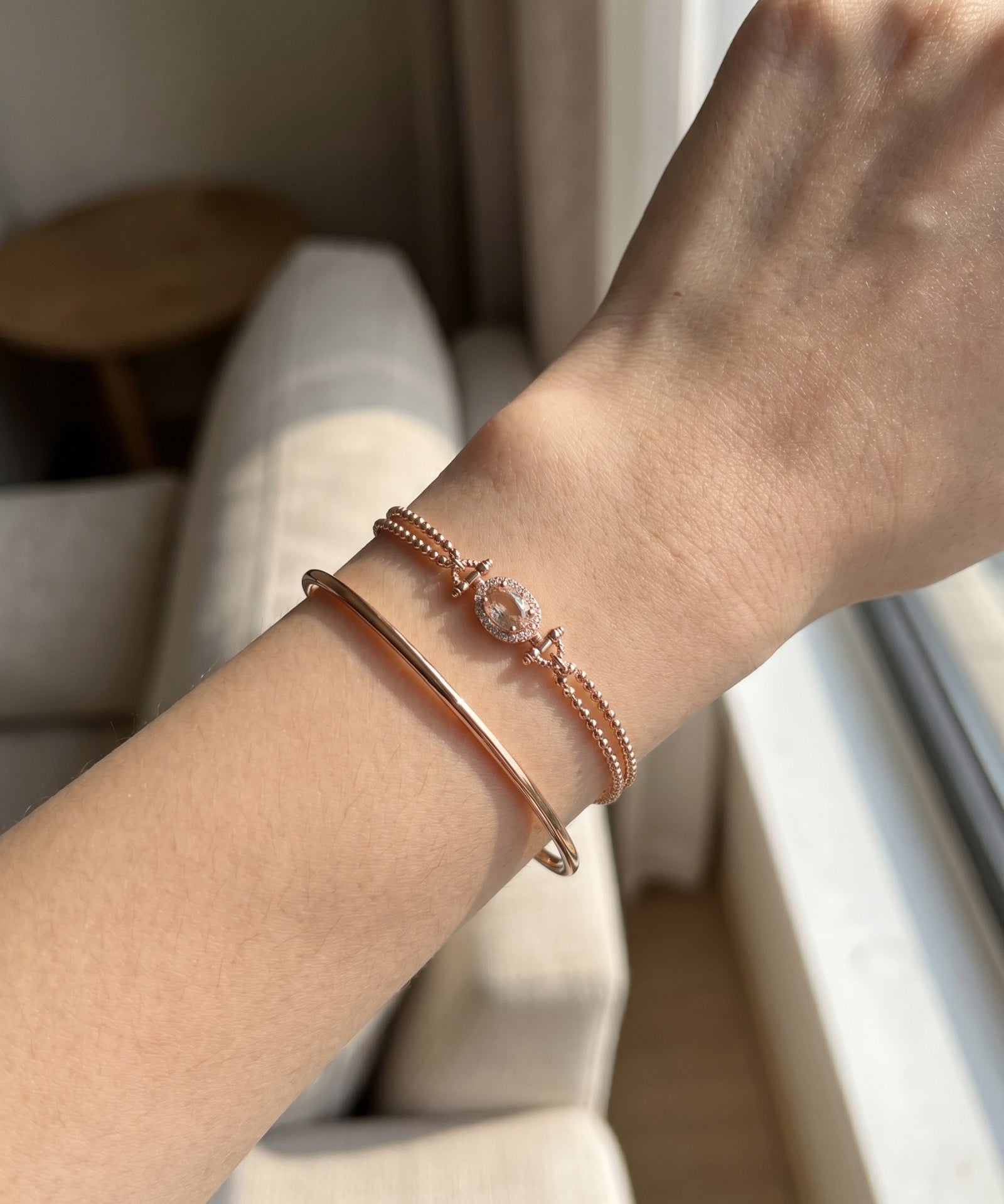 A lifestyle shot of the Constance Petite Morganite Bracelet in rose gold, styled effortlessly on a model to show the scale and brilliance of the oval halo design.