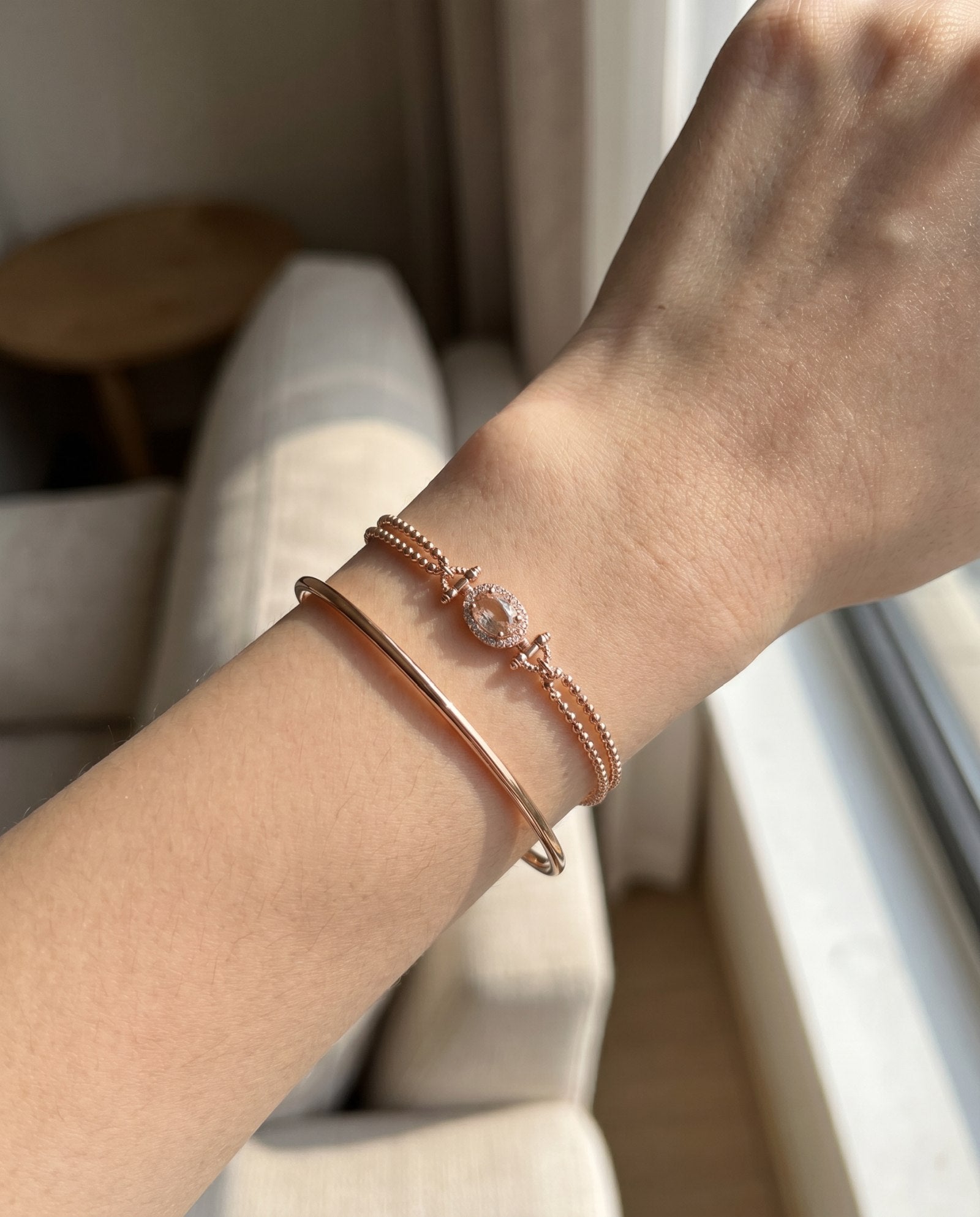 A lifestyle shot of the Constance Petite Morganite Bracelet in rose gold, styled effortlessly on a model to show the scale and brilliance of the oval halo design.