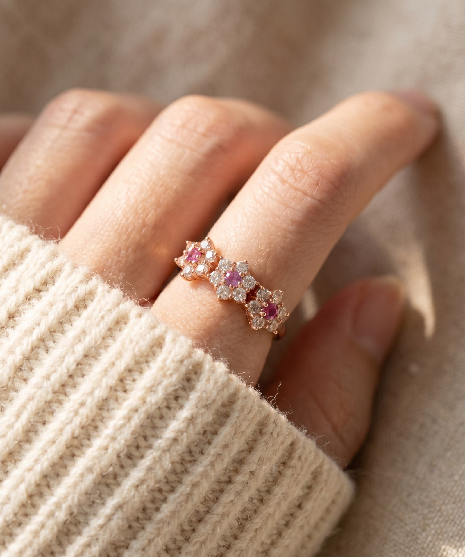Top view of Coquette Bloom Ring i Rose Gold worn on a hand, showing the triple floral garland scale and natural pink sapphire brilliance.