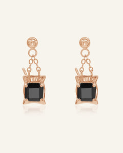 Close-up of the Dabao Kopi Studs | Black Spinel in rose gold, resting on a warm linen background