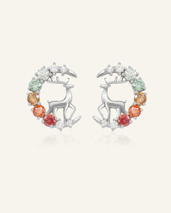 Close-up of the Deer Moissanite Studs in silver, resting on a warm linen background