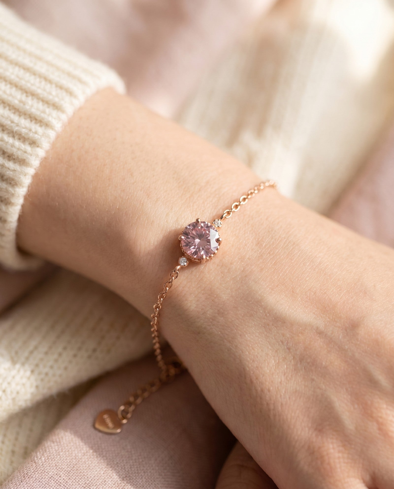 Side view profile of a model wearing a delicate 18k rose gold vermeil bracelet with a round brilliant pink moissanite stone in a scalloped crown setting.