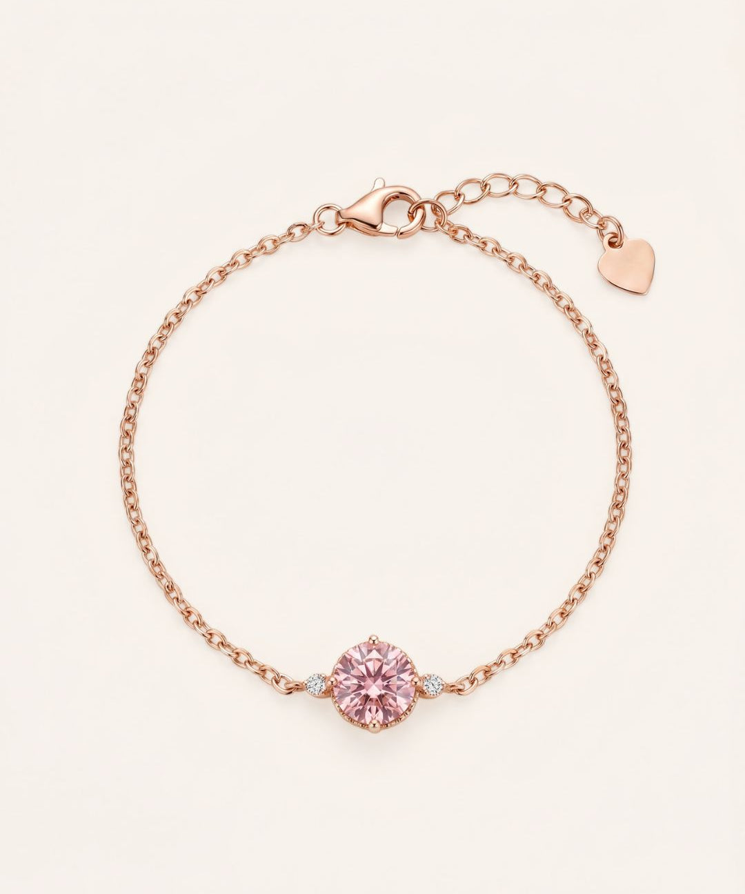 Flat lay view of a romantic 18k rose gold vermeil cable chain bracelet showcasing a 1-carat rose pink brilliant-cut moissanite focal stone flanked by twin accent gems.