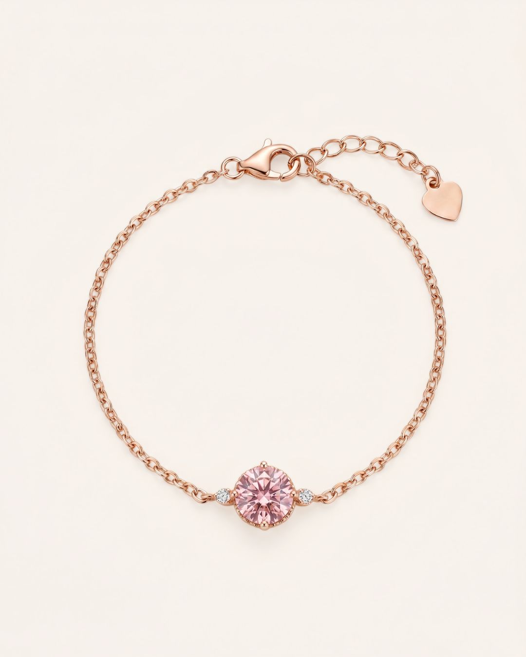 Flat lay view of a romantic 18k rose gold vermeil cable chain bracelet showcasing a 1-carat rose pink brilliant-cut moissanite focal stone flanked by twin accent gems.