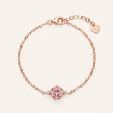 Flat lay view of a romantic 18k rose gold vermeil cable chain bracelet showcasing a 1-carat rose pink brilliant-cut moissanite focal stone flanked by twin accent gems.