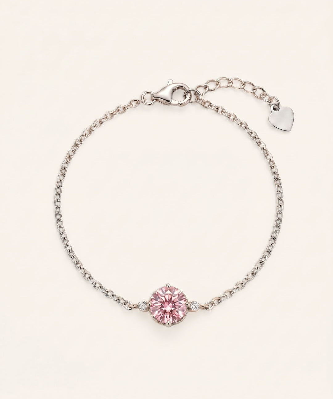 Flat lay view of a 925 sterling silver solitaire bracelet featuring a 1ct round brilliant rose pink moissanite stone, an adjustable extender chain, and a small heart charm.