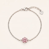Flat lay view of a 925 sterling silver solitaire bracelet featuring a 1ct round brilliant rose pink moissanite stone, an adjustable extender chain, and a small heart charm.