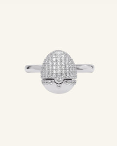 Dragon Egg Ring | White Moissanite, Interactive in silver, resting on a warm linen background