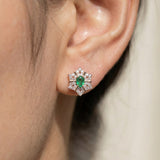 Close-up of a model wearing the Emerald Starflower Studs in rose gold, highlighting the vibrant natural emerald center.