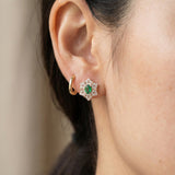 Emerald Starflower Studs in gold styled on a model alongside a simple gold hoop earring for a layered look.