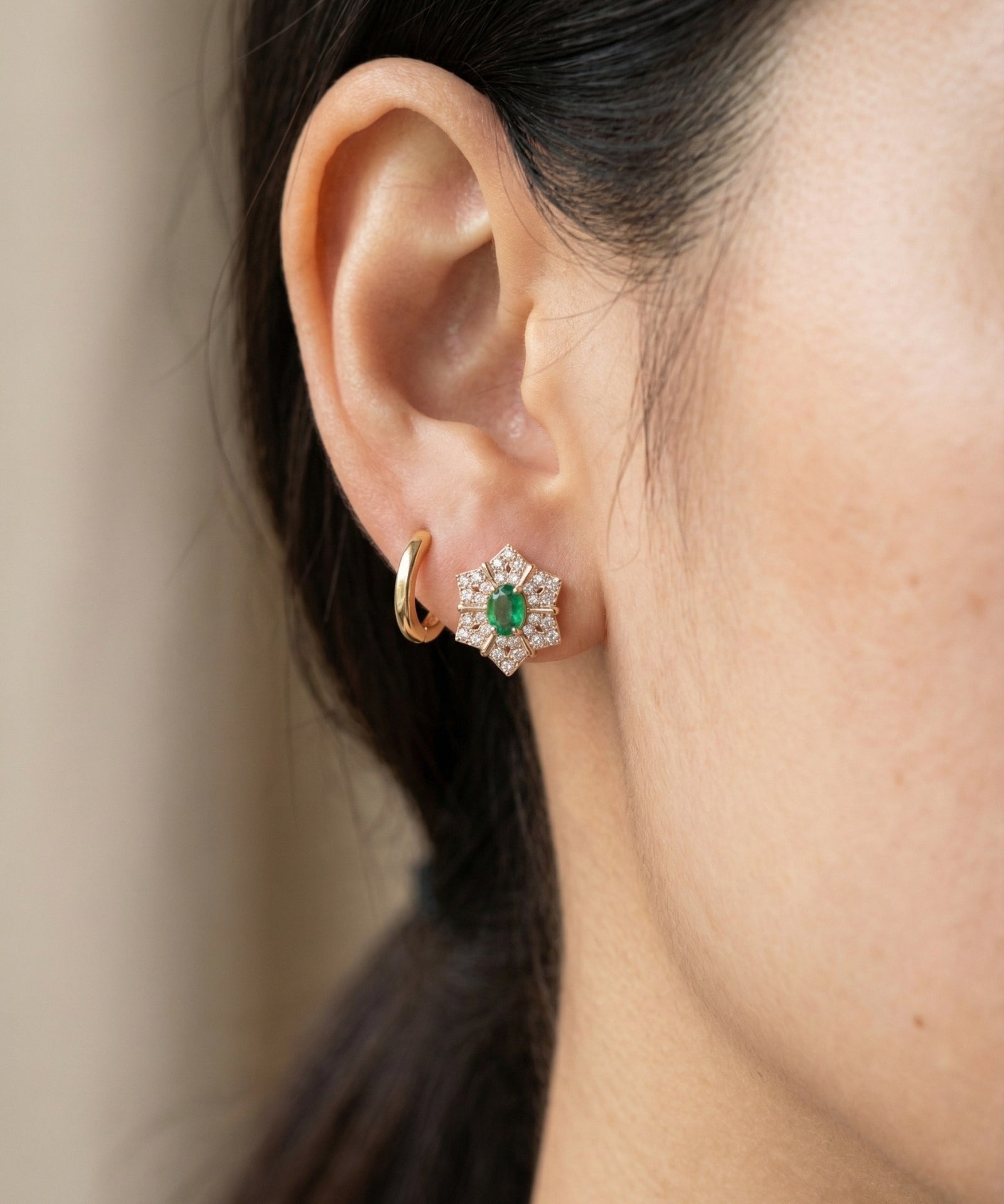 Emerald Starflower Studs in gold styled on a model alongside a simple gold hoop earring for a layered look.