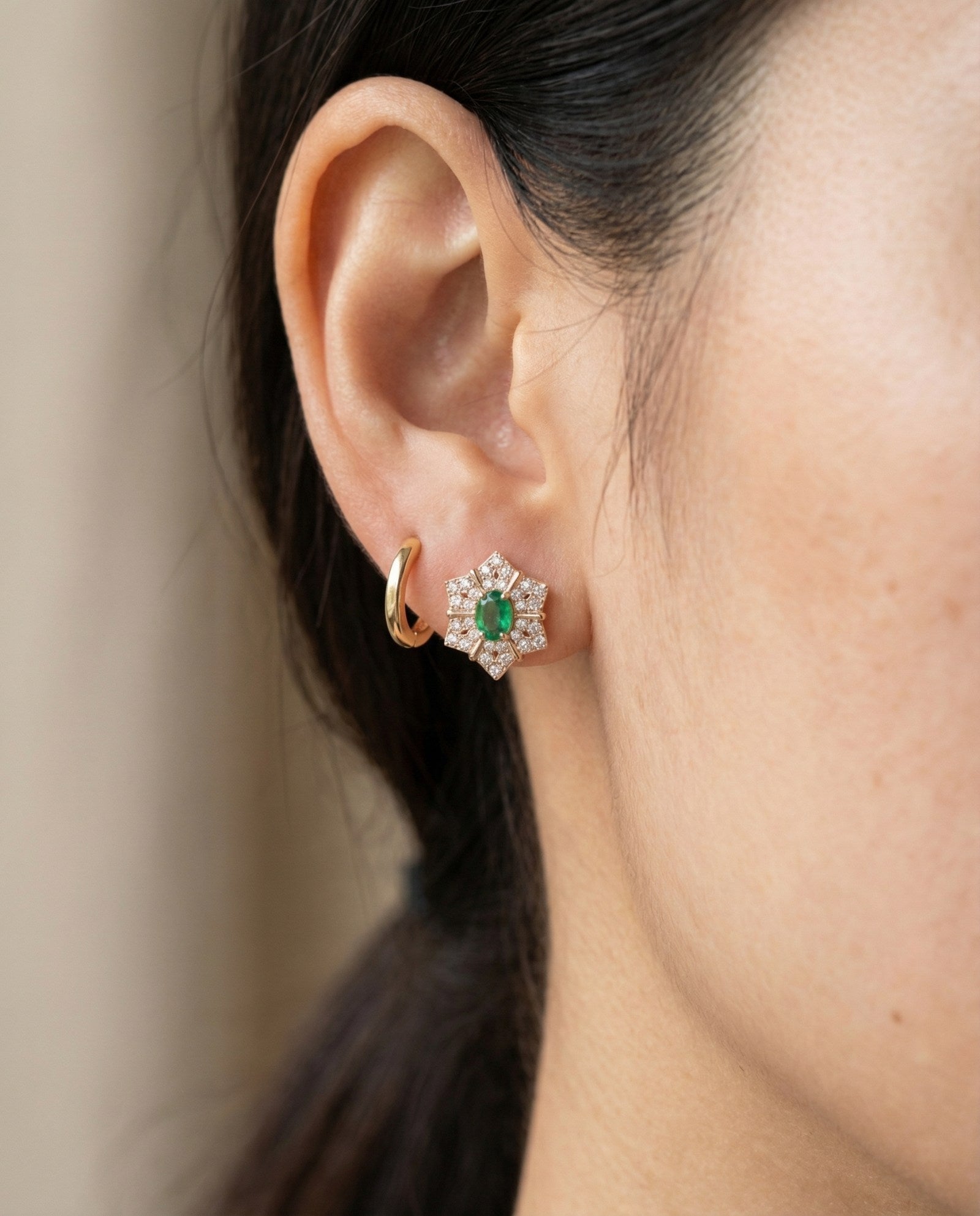 Emerald Starflower Studs in gold styled on a model alongside a simple gold hoop earring for a layered look.
