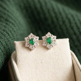 Pair of silver Emerald Starflower Studs displayed in a luxury cream linen jewelry box with a deep green background.